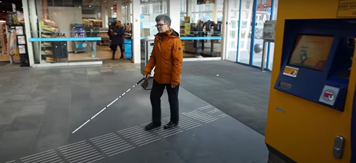 Vrouw loopt met een blindenstok op een treinstation