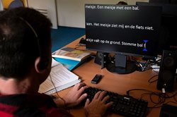 Anderstalige cliënt achter de computer bij Visio Het Loo Erf