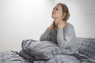 Vermoeide vrouw in bed met handen in haar nek. Foto gemaakt door katemangostar - nl.freepik.com