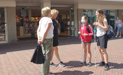 Tiba (rechts) en Marit (links) in een winkelstraat. Zij praten met twee vrouwen.