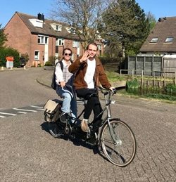 Hannah op de fiets met haar vriend, fietsend in de straat met huizen.