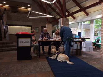 Foto van Willem die zich bij stembureauleden meldt met zijn hond
