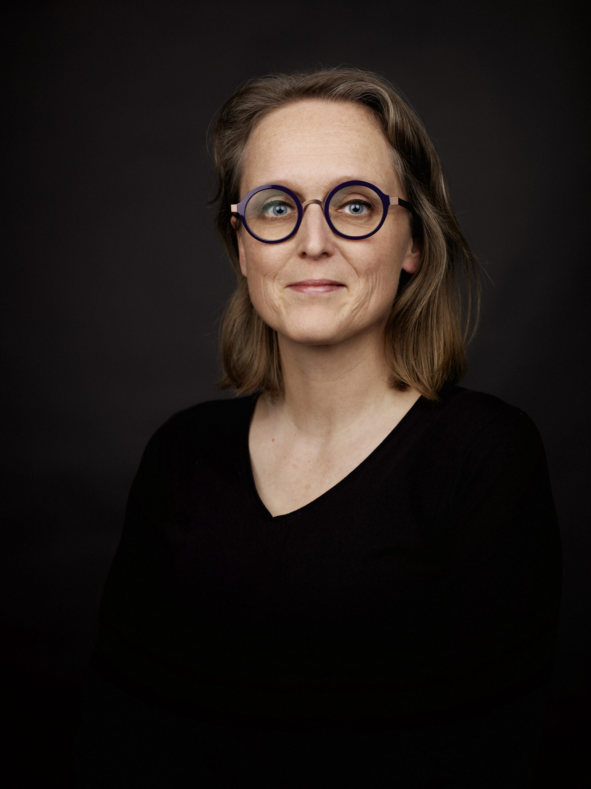 Portret Hanneke Middelburg in zwarte kleding met een zwarte achtergrond