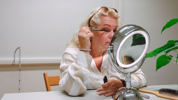Slechtziende vrouw maakt zichzelf op in de spiegel Slechtziende vrouw maakt zichzelf op in de spiegel