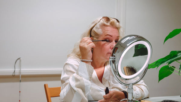 Slechtziende vrouw maakt zichzelf op in de spiegel Slechtziende vrouw maakt zichzelf op in de spiegel