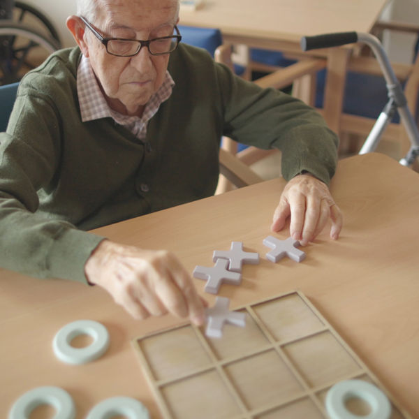 Oudere meneer speelt vergroot spel aan tafel Oudere meneer speelt vergroot spel aan tafel