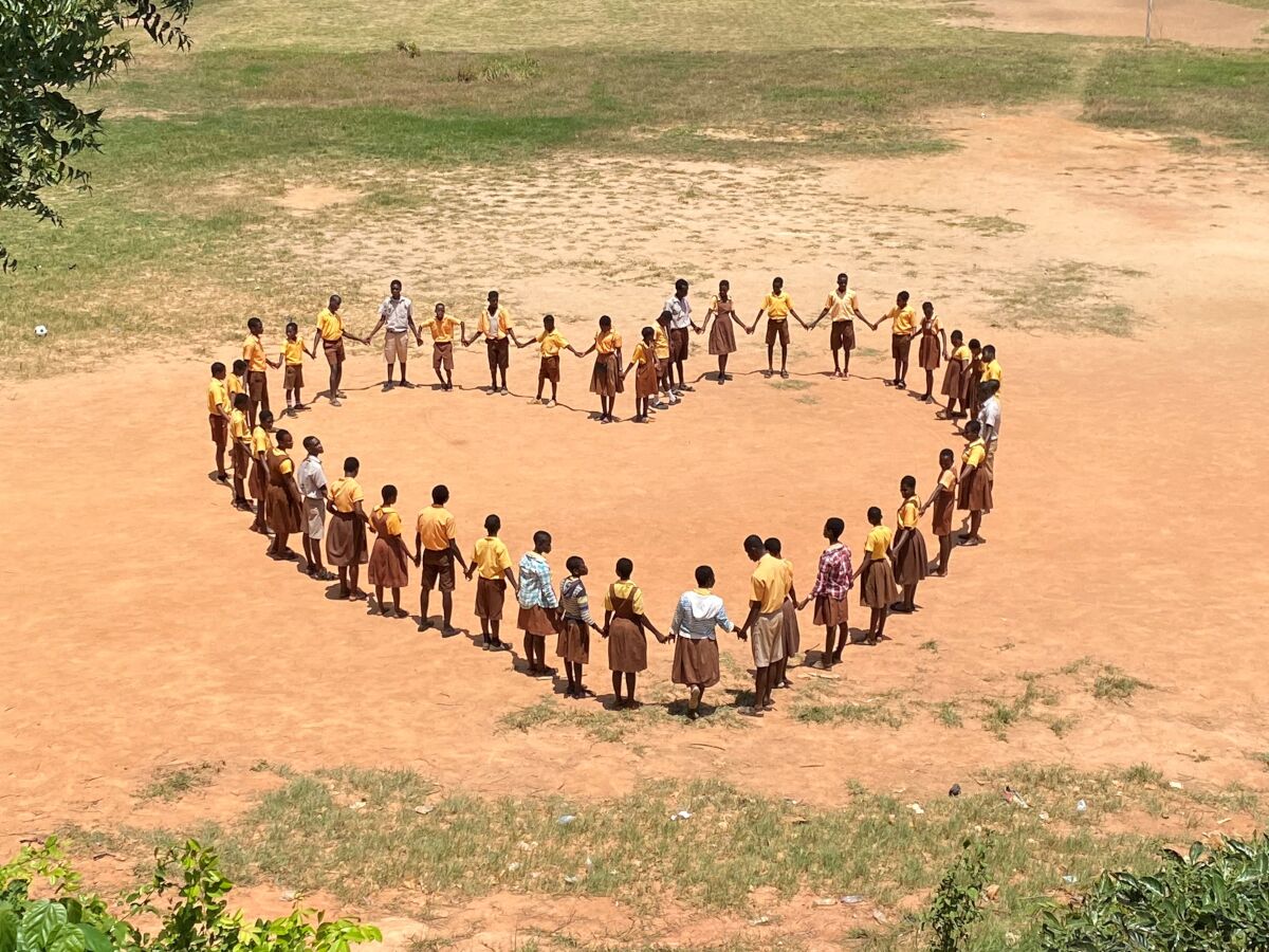 Luchtfoto van kinderen die een hart vormen door elkaars hand vast te houden