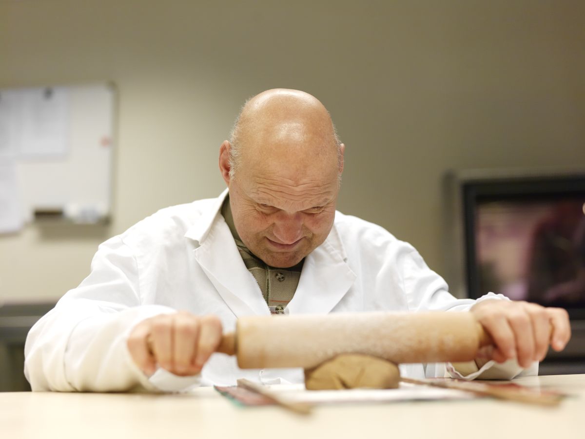 Man met een visuele en verstandelijke beperking rolt deeg uit