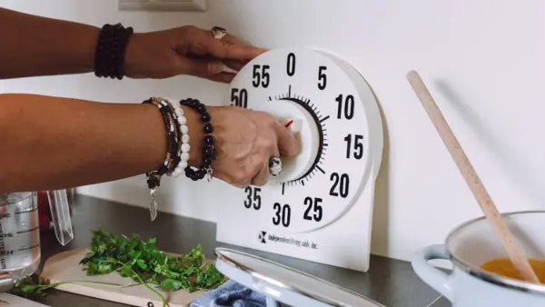 Vrouw gebruikt een kookwekker met grote cijfers in de keuken Vrouw gebruikt een kookwekker met grote cijfers in de keuken