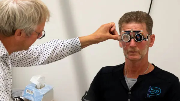 Slechtziende man krijgt onderzoek van optometrist Slechtziende man krijgt onderzoek van optometrist