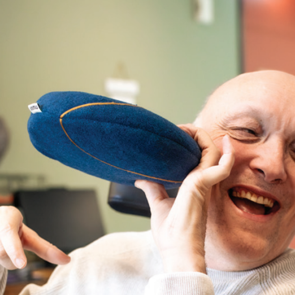 Een cliënt houdt een imnu-kussen tegen zijn gezicht aan. Een cliënt houdt een imnu-kussen tegen zijn gezicht aan.