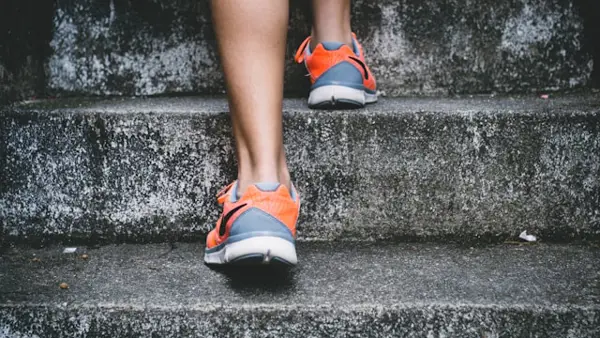 Iemand met sportschoenen aan loopt een trap op. Je ziet alleen de voeten en kuiten. Iemand met sportschoenen aan loopt een trap op. Je ziet alleen de voeten en kuiten.