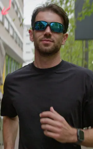 Joost is aan het hardlopen. Hij draagt een zwart sportshirt en een zonnebril. Hij rent richting te camera. Joost is aan het hardlopen. Hij draagt een zwart sportshirt en een zonnebril. Hij rent richting te camera.