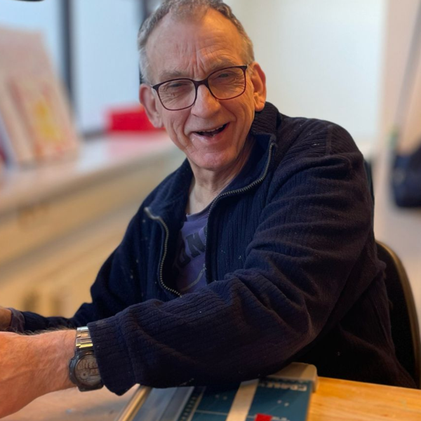 Mannelijke cliënt werkt aan tafel met een papiersnijapparaat Mannelijke cliënt werkt aan tafel met een papiersnijapparaat