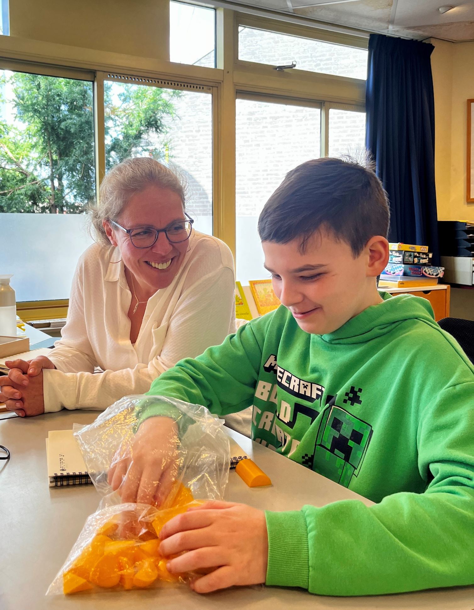 Dean met ambulant onderwijskundig begeleider van Visio aan tafel in een klaslokaal