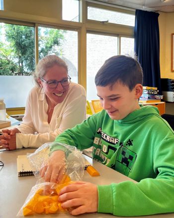 Dean met ambulant onderwijskundig begeleider van Visio aan tafel in een klaslokaal Dean met ambulant onderwijskundig begeleider van Visio aan tafel in een klaslokaal