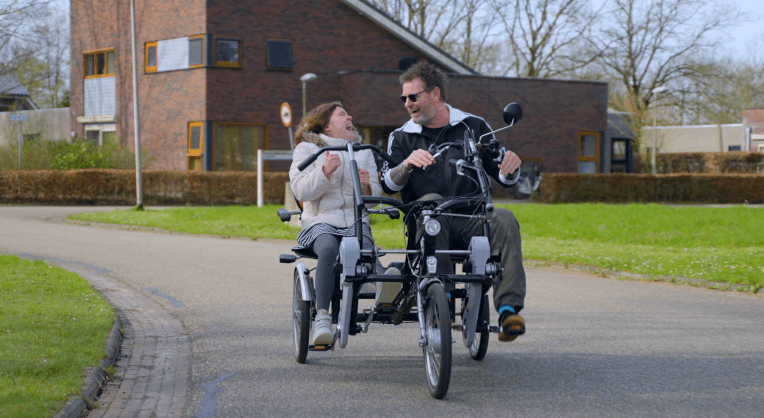 Cliënt met visuele en verstandelijke beperking en begeleider fietsen op de duofiets