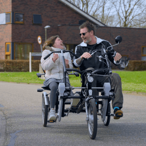 Cliënt met visuele en verstandelijke beperking en begeleider fietsen op de duofiets Cliënt met visuele en verstandelijke beperking en begeleider fietsen op de duofiets