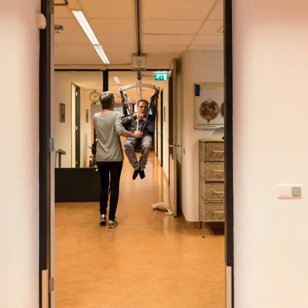 Begeleider ondersteunt cliënt in tillift bij Visio Wonen & Dagbesteding Emmen Begeleider ondersteunt cliënt in tillift bij Visio Wonen & Dagbesteding Emmen