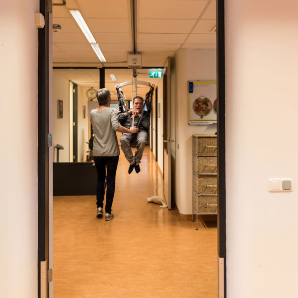 Begeleider ondersteunt cliënt in tillift bij Visio Wonen & Dagbesteding Emmen Begeleider ondersteunt cliënt in tillift bij Visio Wonen & Dagbesteding Emmen
