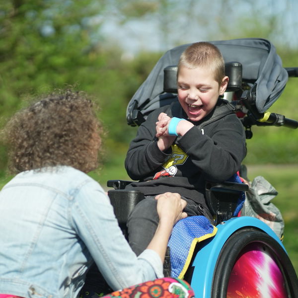 Medewerker en jonge cliënt met een meervoudige beperking in rolstoel Medewerker en jonge cliënt met een meervoudige beperking in rolstoel