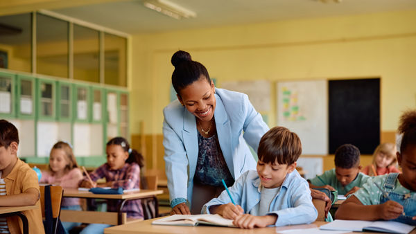 Ambulante onderwijskundige begeleider helpt leerling aan bureau. Ambulante onderwijskundige begeleider helpt leerling aan bureau.