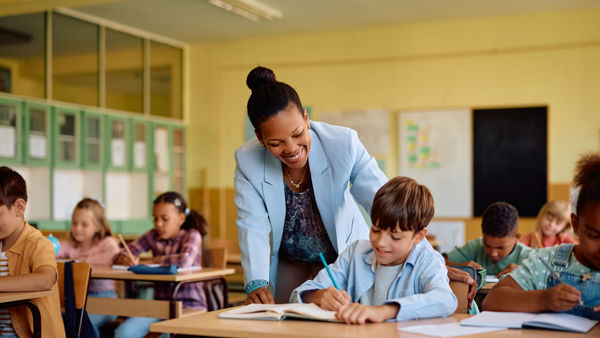 Ambulante onderwijskundige begeleider helpt leerling aan bureau. Ambulante onderwijskundige begeleider helpt leerling aan bureau.