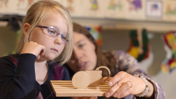 Slechtziend meisje speelt samen met een begeleider met houten speelgoed. Slechtziend meisje speelt samen met een begeleider met houten speelgoed.