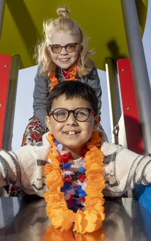 Twee kinderen, een jongen en een meisje, gaan samen van de glijbaan af. De jongen steekt zijn duimen omhoog. Twee kinderen, een jongen en een meisje, gaan samen van de glijbaan af. De jongen steekt zijn duimen omhoog.