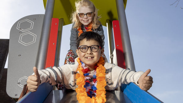 Twee kinderen, een jongen en een meisje, gaan samen van de glijbaan af. De jongen steekt zijn duimen omhoog. Twee kinderen, een jongen en een meisje, gaan samen van de glijbaan af. De jongen steekt zijn duimen omhoog.
