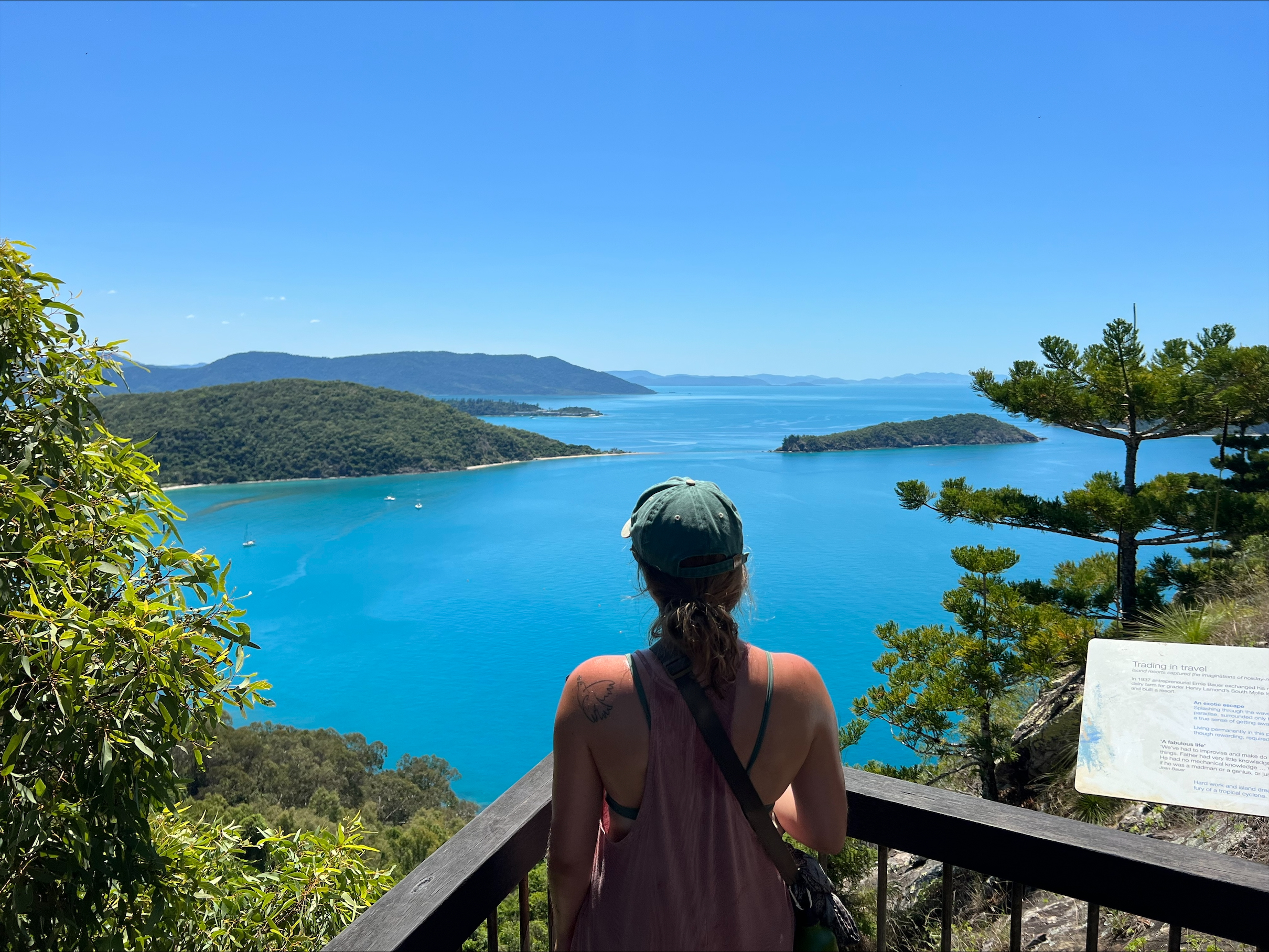 Hanna staat met haar rug naar de camera. Ze kijkt uit over een blauw meer. 