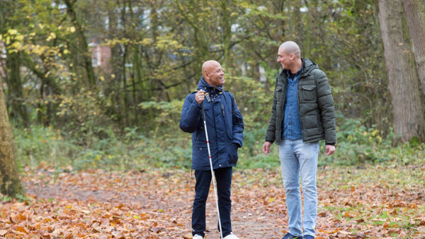 Cliënt loopt samen met ambulant specialistisch begeleider door het bos. Cliënt loopt samen met ambulant specialistisch begeleider door het bos.