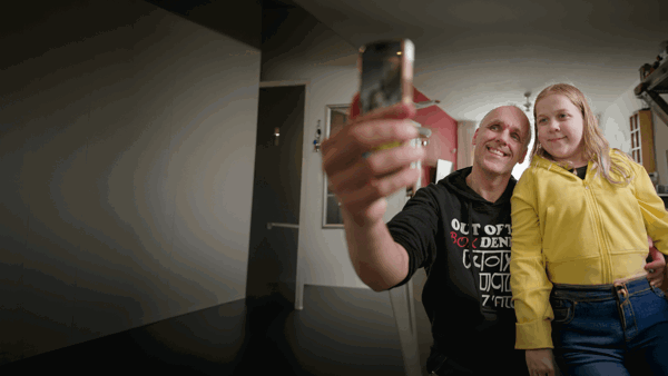 Een slechtziende man van middelbare leeftijd en zijn dochter van ongeveer 13 jaar maken samen een selfie. Ze kijken allebei lachend naar de camera van de telefoon. Een slechtziende man van middelbare leeftijd en zijn dochter van ongeveer 13 jaar maken samen een selfie. Ze kijken allebei lachend naar de camera van de telefoon.