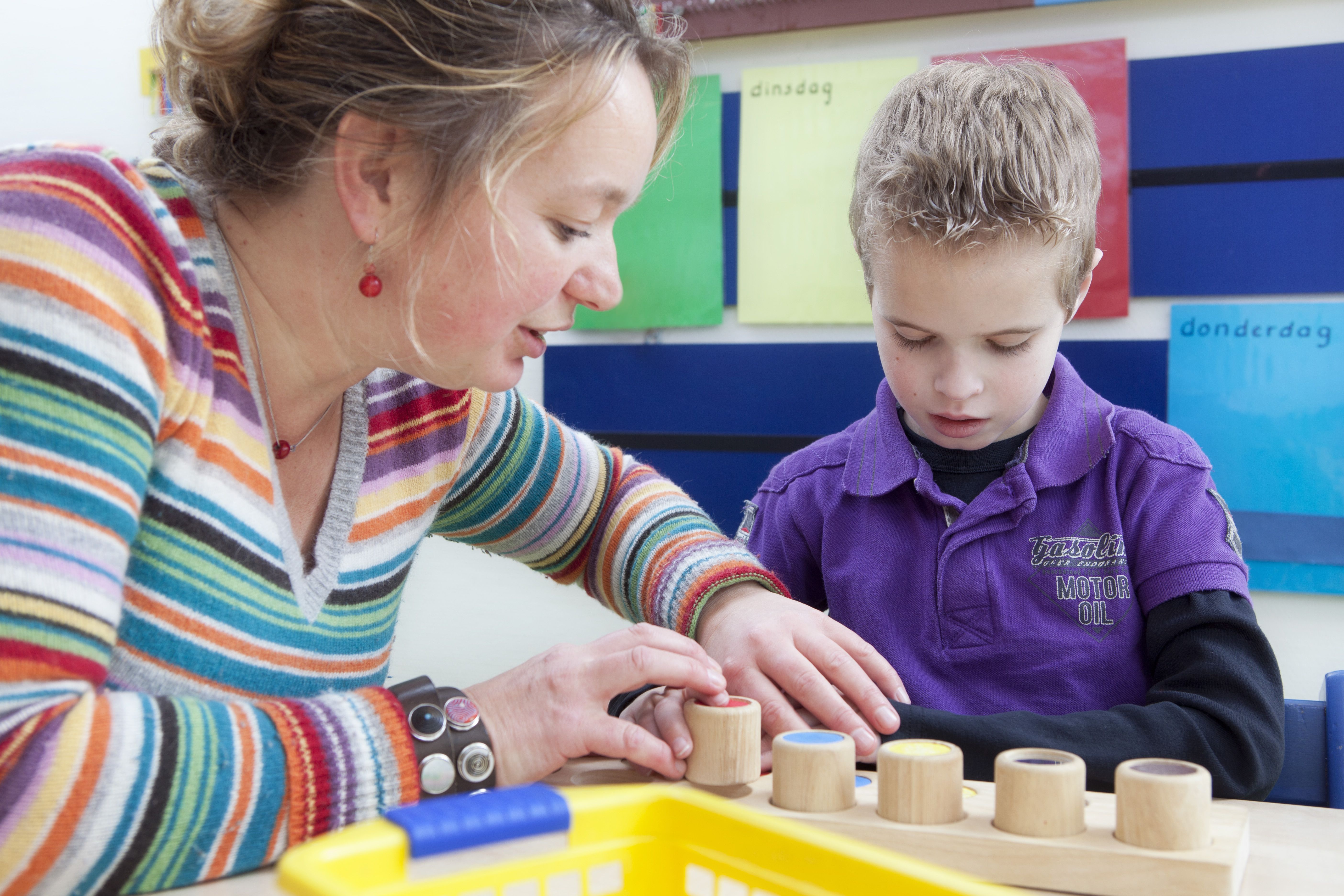 Begeleider helpt leerling met blokken spelen. 