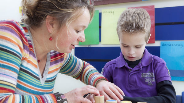 Begeleider helpt leerling met blokken spelen. Begeleider helpt leerling met blokken spelen.