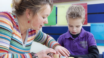 Begeleider helpt leerling met blokken spelen. Begeleider helpt leerling met blokken spelen.