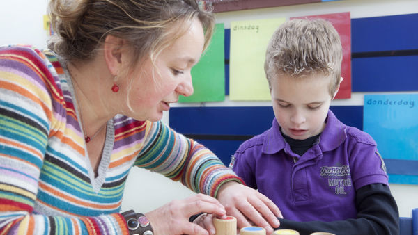 Begeleider helpt leerling met blokken spelen. Begeleider helpt leerling met blokken spelen.