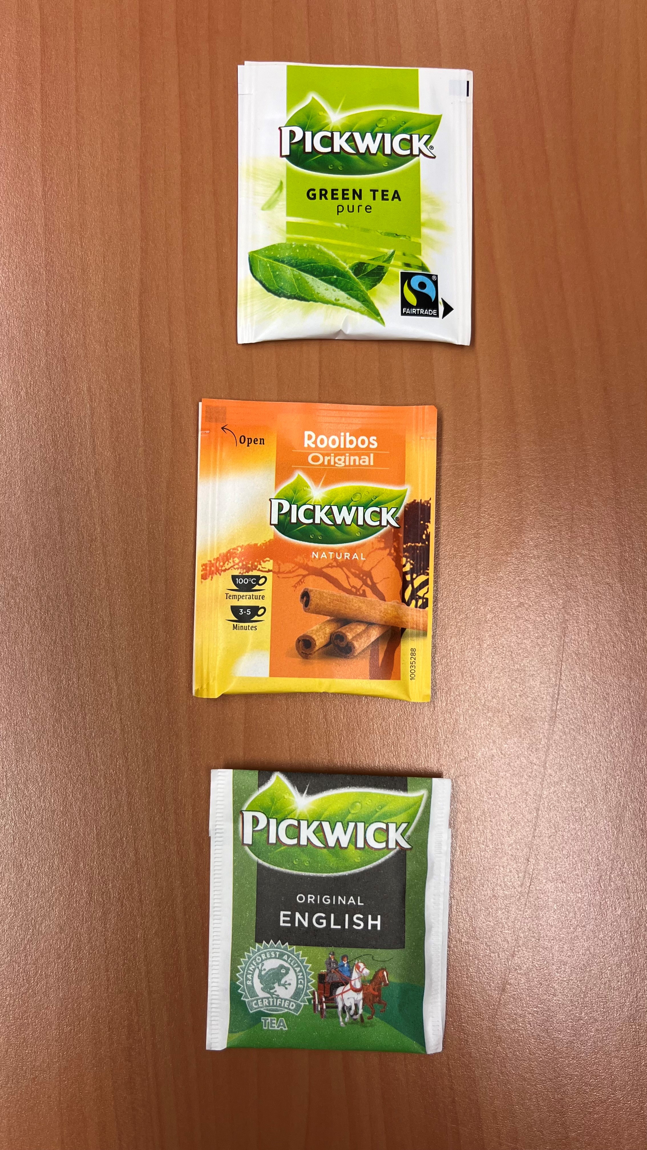 “Drie Pickwick-theezakjes op een houten ondergrond. 
