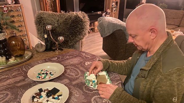 Fred zit aan een ronde tafel. Hij is bezig met een bouwpakket. De onderdelen liggen op twee borden voor hem. Fred zit aan een ronde tafel. Hij is bezig met een bouwpakket. De onderdelen liggen op twee borden voor hem.