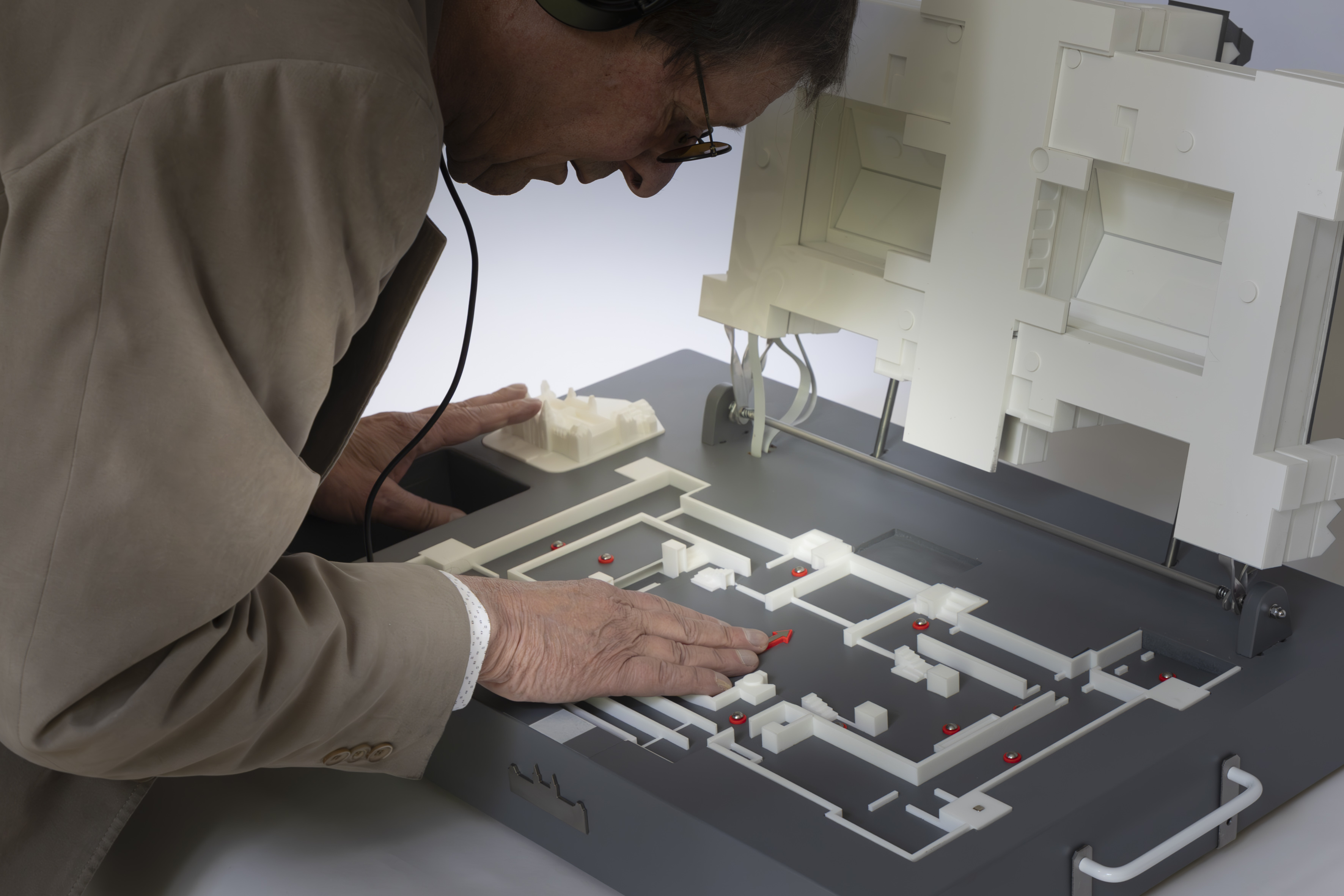 Hannes staat voorovergebogen over een maquette heen. Hij heeft zijn hand op de maquette. 
