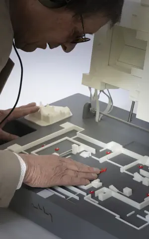 Hannes staat voorovergebogen over een maquette heen. Hij heeft zijn hand op de maquette. Hannes staat voorovergebogen over een maquette heen. Hij heeft zijn hand op de maquette.
