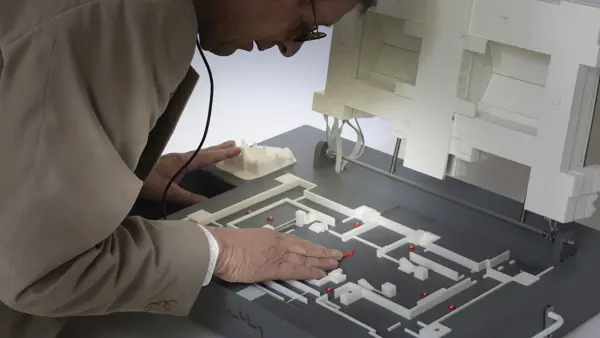 Hannes staat voorovergebogen over een maquette heen. Hij heeft zijn hand op de maquette. Hannes staat voorovergebogen over een maquette heen. Hij heeft zijn hand op de maquette.