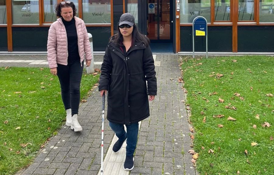 visio-het-loo-erf-Athittiya-Auaychai-loopt-met-stok-begeleid-door-medewerkerk.jpg (1)