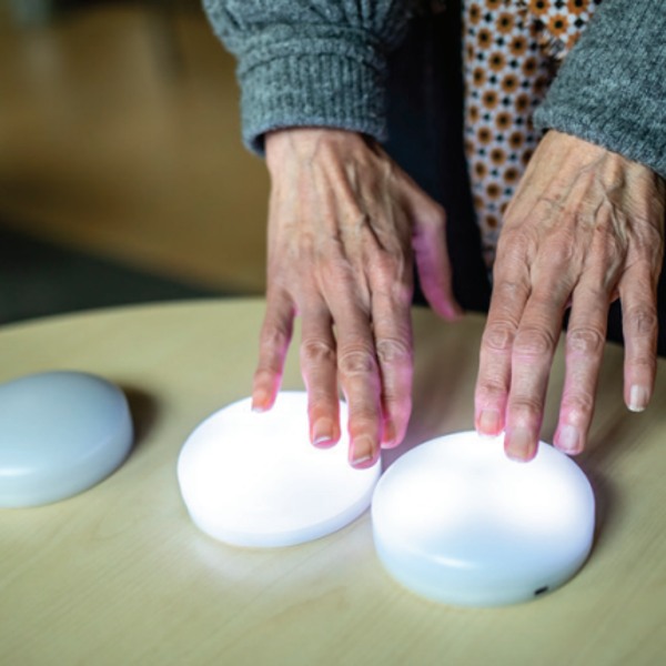 Er liggen drie knoppen op tafel. Twee handen liggen op twee van de knoppen. Er liggen drie knoppen op tafel. Twee handen liggen op twee van de knoppen.