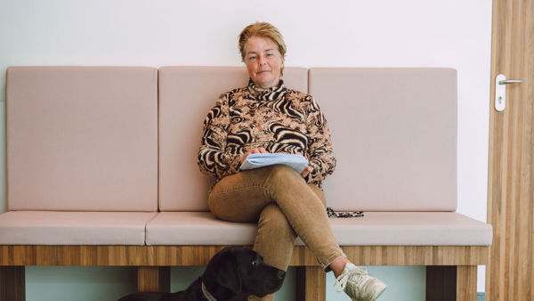 Blinde vrouw zit op bankje met haar geleidehond voor zich Blinde vrouw zit op bankje met haar geleidehond voor zich