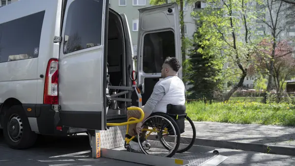 Rolstoelgebruiker rijdt een oprijplaat op bij een rolstoelbus Rolstoelgebruiker rijdt een oprijplaat op bij een rolstoelbus