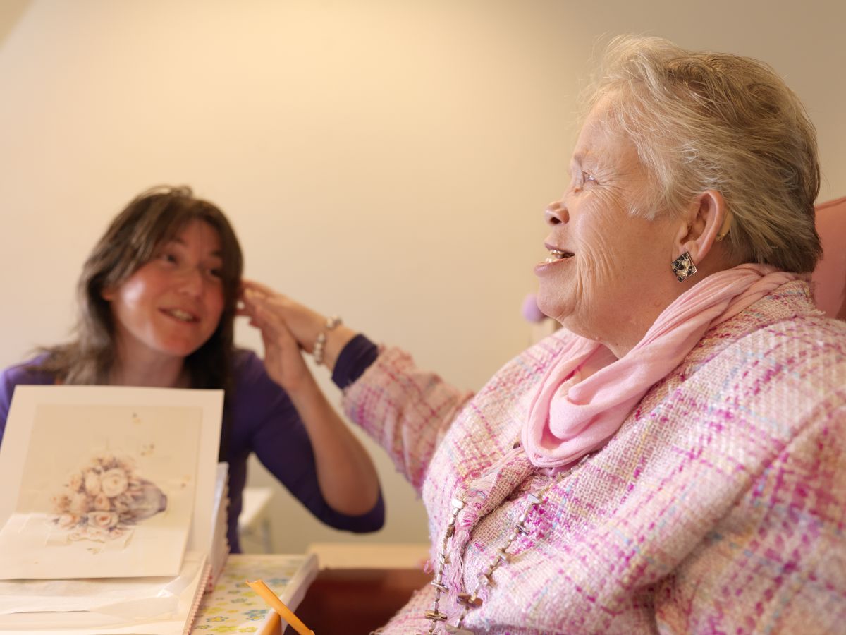 Oudere dame met visuele en verstandelijke beperking en een medewerker