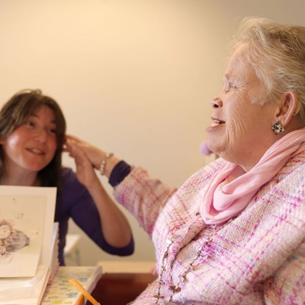 Oudere dame met visuele en verstandelijke beperking en een medewerker Oudere dame met visuele en verstandelijke beperking en een medewerker