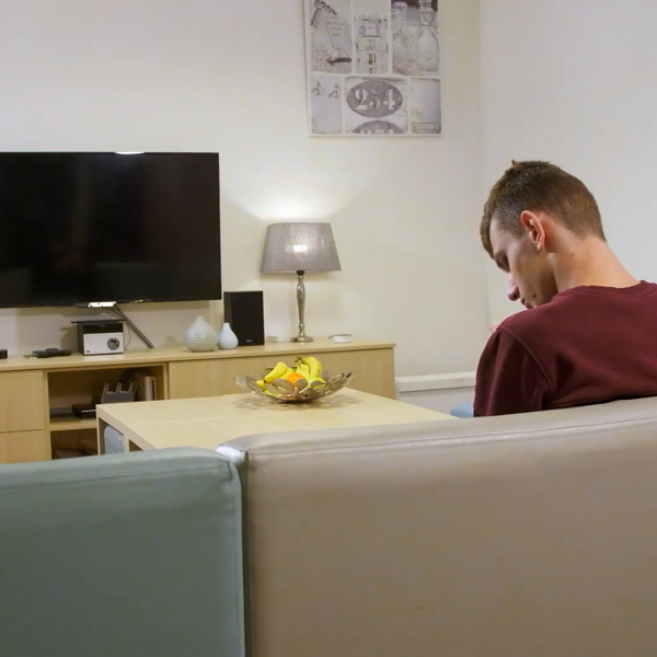 Jonge man met een visuele beperking zit in een woonkamer op de bank Jonge man met een visuele beperking zit in een woonkamer op de bank