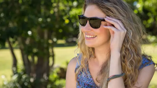 Volwassen vrouw is buiten in de natuur en draagt een zonnebril Volwassen vrouw is buiten in de natuur en draagt een zonnebril